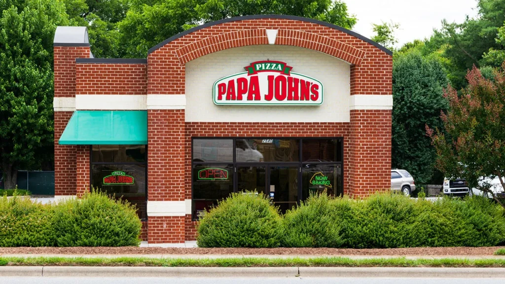 A brick building with a green awning and "Papa John's" sign, featuring an open sign in the window. Is Papa John's open on Labor Day?